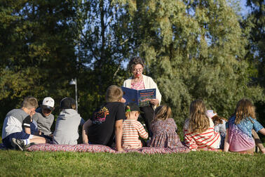 Seniori lukee puistossa lapsille