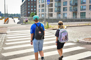 Två barn som går över gatan på ett övergångsställe.