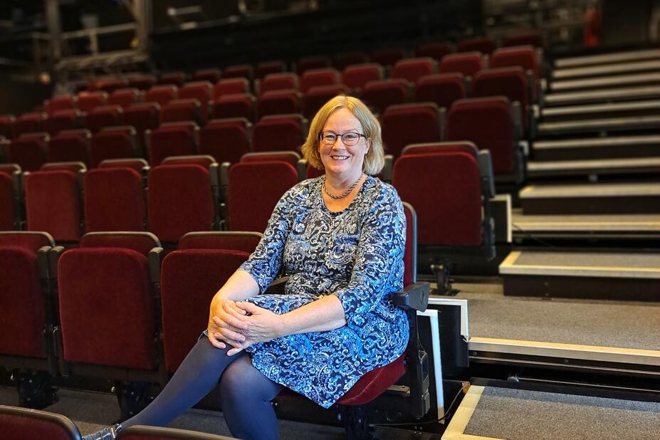 Nina Gran sitter i en tom rad av teaterstolar.